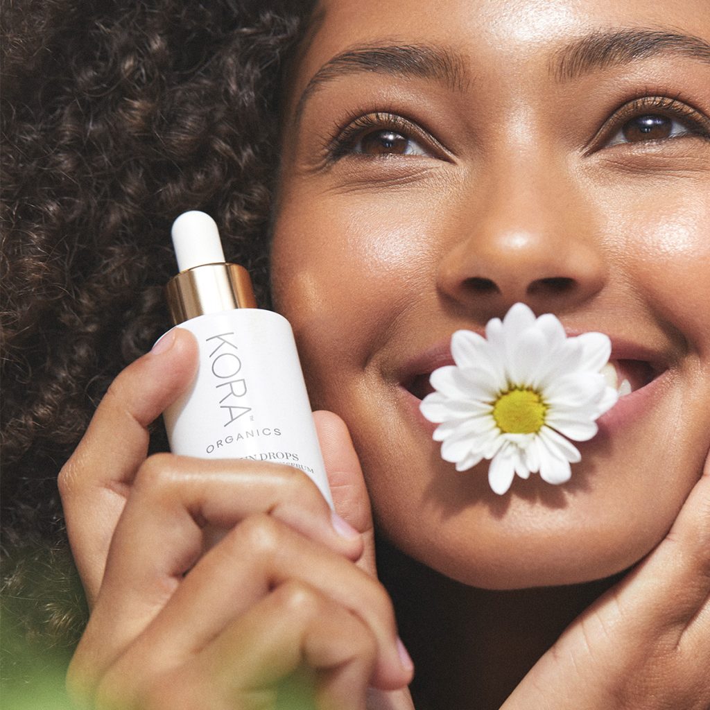 Woman holding SPF bottle with smiling with flower in mouth